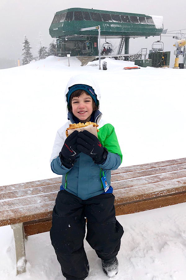 Little boy enjoying a snack after skiing at Snowshoe Mountain WV.