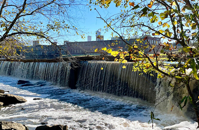 Waterfall at Battle Park with Rocky Mount Mills in the background featured by top US family travel blog, More than Main Street.