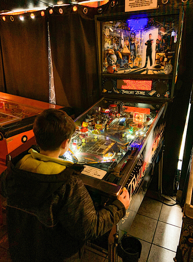 Boy playing a pinball machine in the Pinball Museum in Asheville NC.