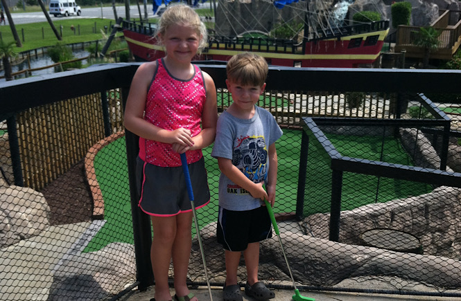 A little girl and a little boy playing miniature golf in the Outer Banks of North Carolina..