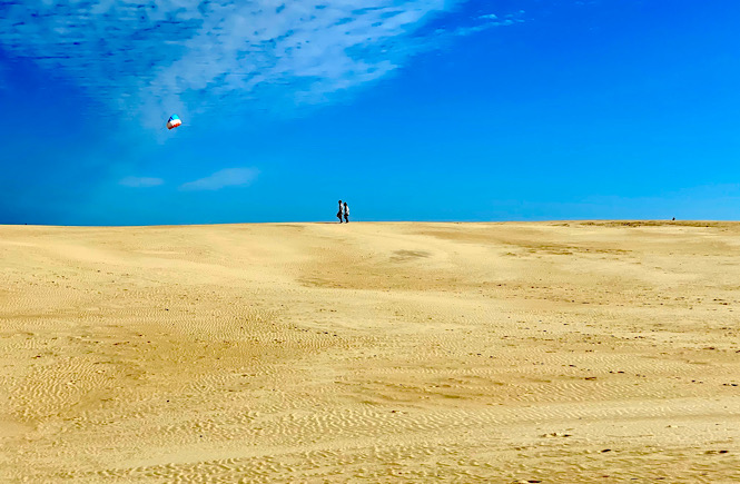 Jockey's Ridge State Park sand dunes! Image is someone flying a kite in the distance on empty sand dunes.