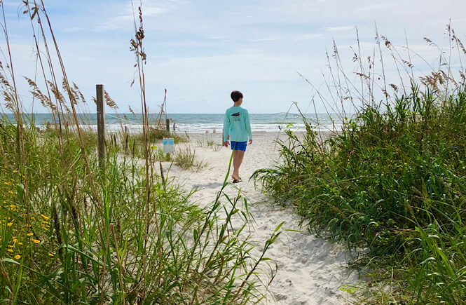 A boy walking to the Wrightsville Beach Mailbox.