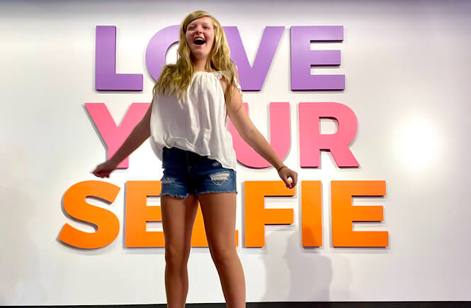 "Love your selfie" sign with a teenager girl jumping for joy!