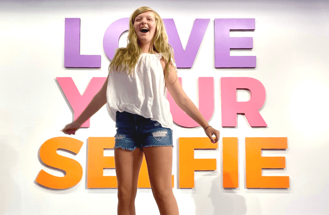 101 powerful self love affirmations: Love your selfie sign with girl exuding joy and happiness!