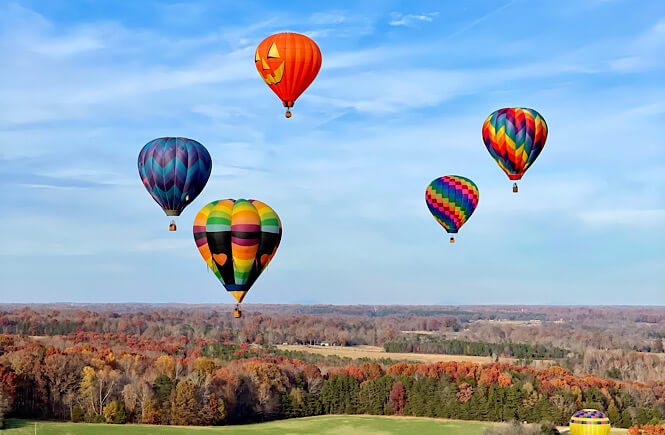 Five hot air balloons floating in the air over beautiful Statesville NC in the fall.