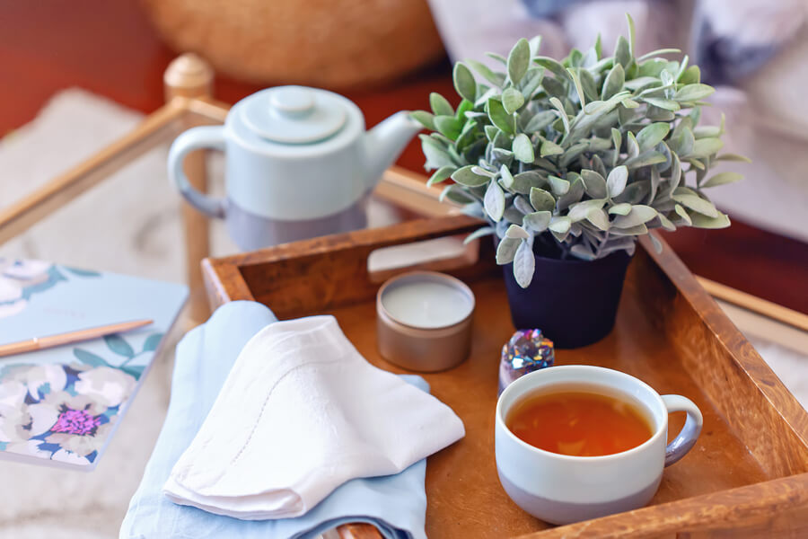 Simple pleasures in life that can make you happier: image of a cup of tea on a coffee table with a succulent and teapot which are examples of beautiful simple things.