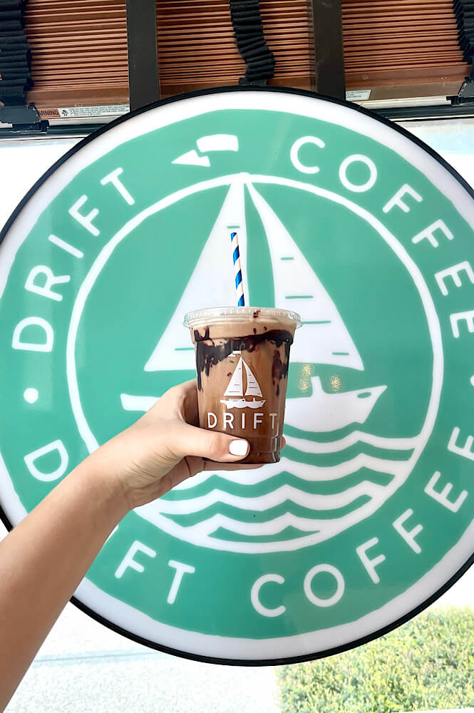iced specialty coffee drink in front of the Drift Coffee sign