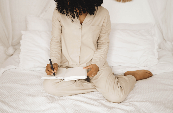 woman in pajamas journaling in bed