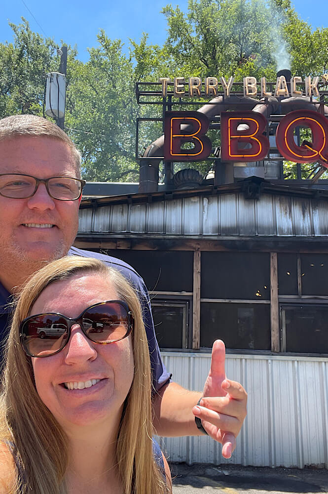 selfie of a couple in Austin Texas in front of Terry Black's BBQ- traveling for the food scene