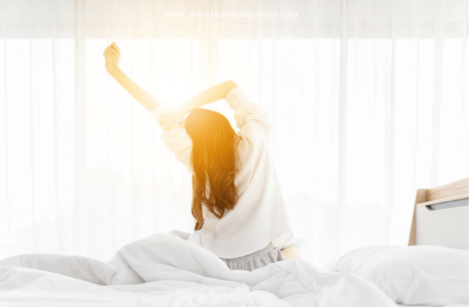 woman stretching in bed in front of a window