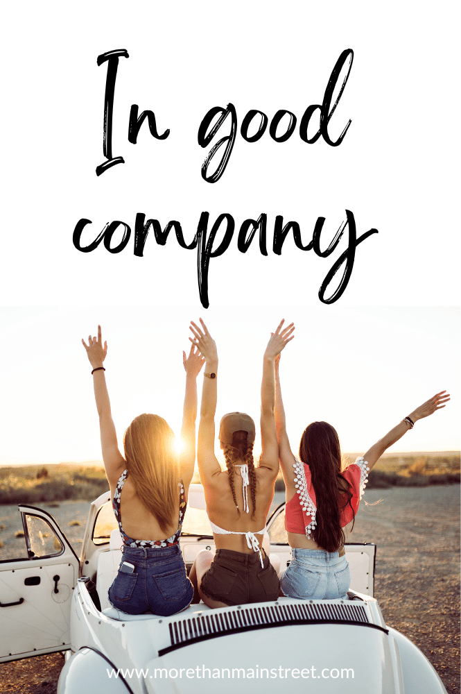 Three women with their hands in the air in a convertible with caption "In good company"