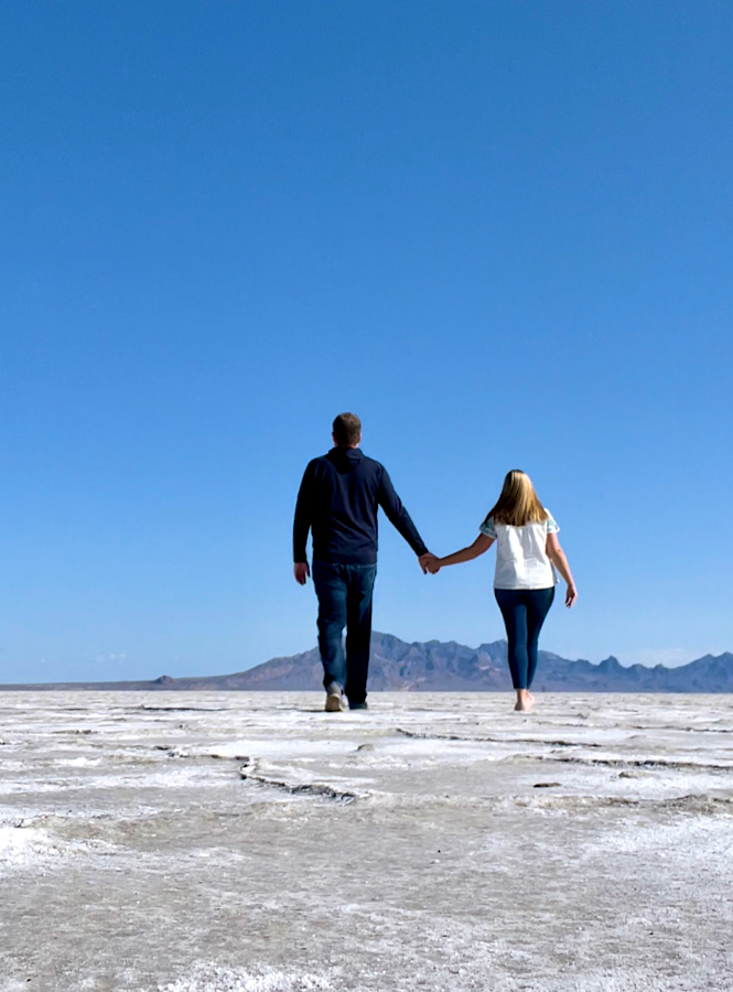 couple holding hands walking away from the camera at the Salt Flats in utah because it shows connection which is an important habit of a slower lifestyle