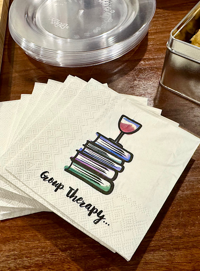 Napkins that say book therapy with a stack of four books and a glass of wine on top is a super cute addition to any book club meeting.