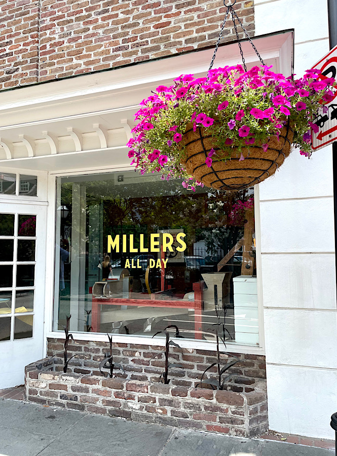 The exterior of Millers All Day in Charleston with a pink flower hanging basket out front is our favorite brunch spot.