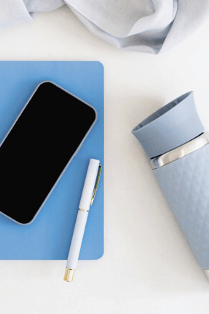 Travel essentials: Travel journal, phone, pen and water bottle.