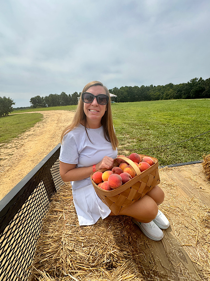 Woman on a hayride after picking peaches at the peach orchard delighting in the whimsy of the activity.